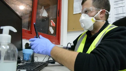 A masked man at a table works on a computer in office. Stock Footage 127191898