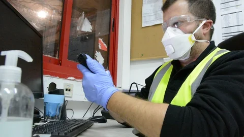 A masked man at a table works on a computer in office. Stock Footage 127191938