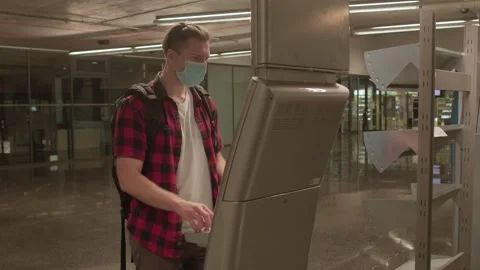 A masked man uses a machine while crossing public transport. Stock-Footage 166051188