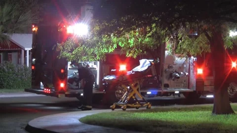Masked Paramedic Pushing Empty Gurney at Night with Flashing Fire Truck Lights Stock Footage 161374459