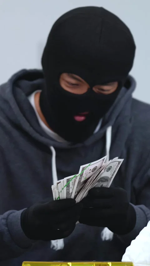 Masked Robber in Black Balaclava Counting Stolen Cash and Gold Bars Stock Footage 331561657