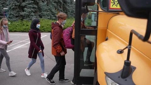 Masked students taking turns boarding school bus Stock Footage 169649828