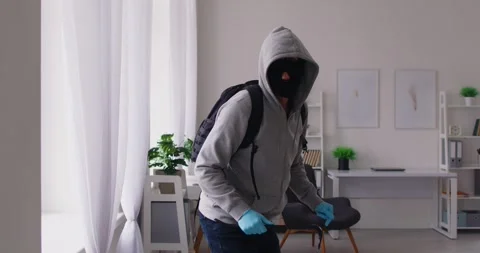 Masked thief climbing through window into apartment, committing burglary and Stock Footage 317607777