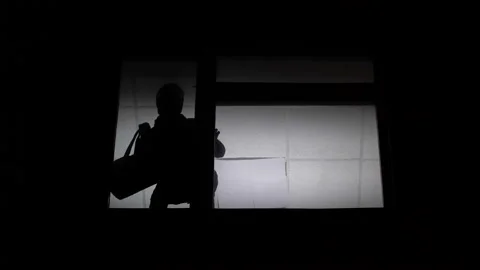 Masked thief escaping from robbed flat with money bag, silhouette in window Stock Footage 98966522