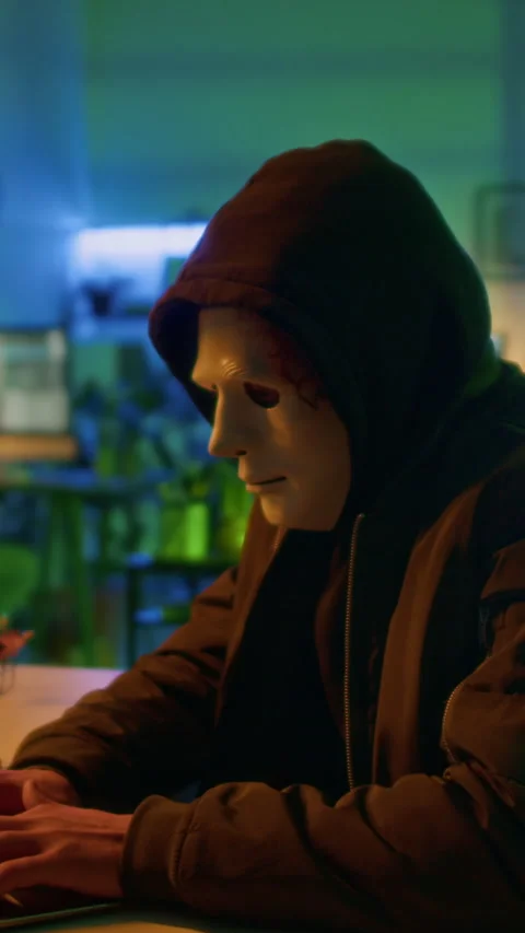 Masked Threat Actor Working on Laptop Causing Damage to Companys Reputation Stock Footage 299239932