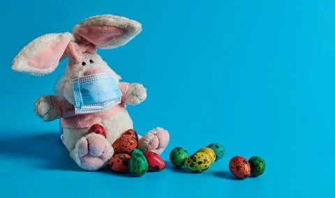 Masked white hare and easter eggs lie Stock Photos