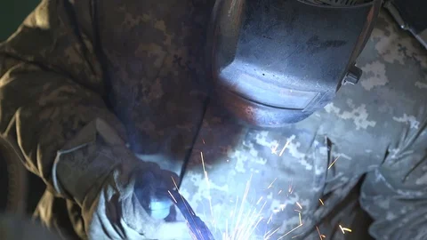 Masked worker welding with a curvy device and a spray of blue plazma sparkles Stock Footage 105449005