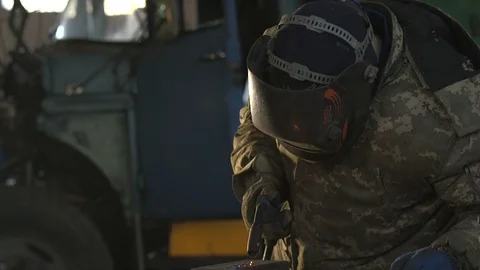 Masked worker welding a rectangular metallic tube with a spew of plazma sparkles Stockbeeldmateriaal 105449098