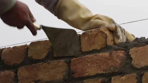 Mason Building Wall with Bricks and Cement Stock Footage 144924696
