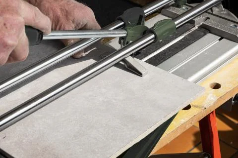 The mason cuts a ceramic tile with a tile cutter Stock Photos