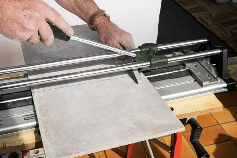 The mason cuts a ceramic tile with a tile cutter Stock Photos