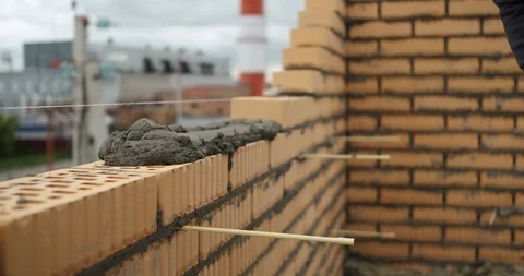 Mason erects a wall of a brick building in the industrial zone of the city Stock Footage 116812933