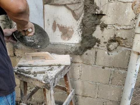 Mason plastering rough surface of old wall at repair site Stock Photos