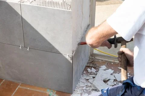 The mason prepares the wall with a chisel before laying a ceramic tile Stock Photos