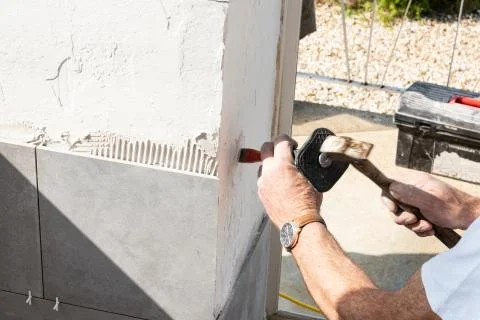 The mason prepares the wall with a chisel before laying a ceramic tile Stock Photos