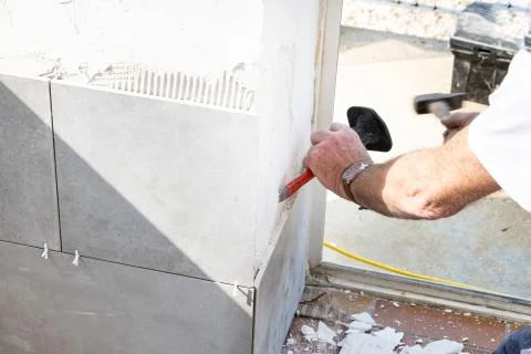 The mason prepares the wall with a chisel before laying a ceramic tile Stock Photos