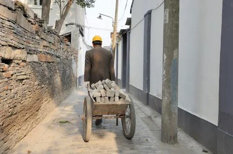 Mason pulling a cart with bricks Stock Photos