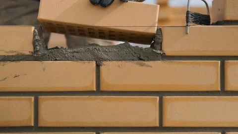 Mason worker Inserts Brick into Brickwork, Builder Laying Straw-colored Brick Stock Footage 129499889