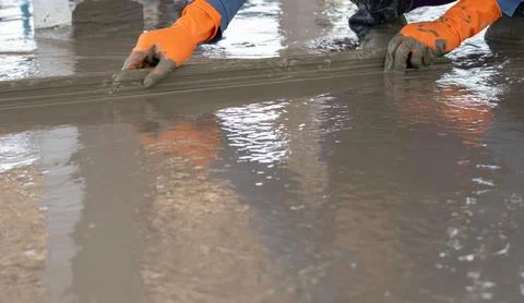 Mason worker working with trowel to level cement floor at construction site.. 스톡 사진
