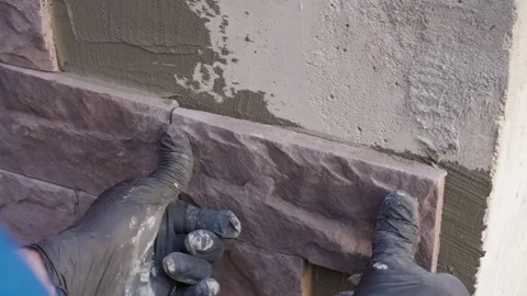 Masonry work as a construction worker installs decorative stone on a wall Video stock 318471311