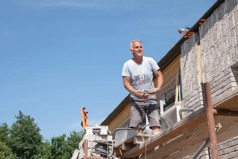 Masonry worker the bricklayer makes the facade of the house from gray bricks Stock Photos