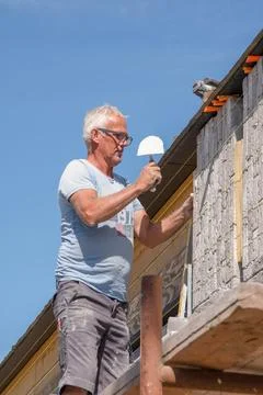 Masonry worker the bricklayer makes the facade of the house from gray bricks Stock Photos