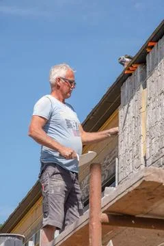 Masonry worker the bricklayer makes the facade of the house from gray bricks Stock Photos