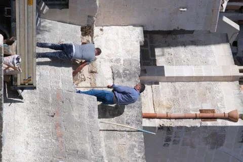 Masons at work in the construction of a wall with stone blocks in Matera. Stock Photos