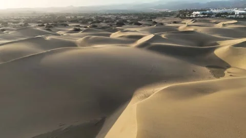 Maspalomas sand dunes glow in warm sunlight near buildings and mountains Vídeos de archivo 345948823