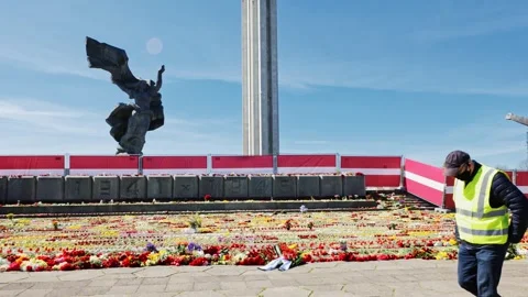 Mass of Flowers Cover Monument Base in Riga, May 9 - Worker Passes Latvian Flags Stock Footage 306126967
