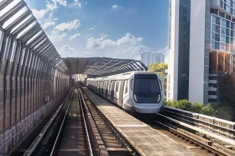 Mass rail transit train passing through tracks with sound barrier in the city Fotos de archivo