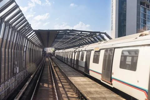 Mass rail transit train passing through tracks with sound barrier in the city Stock Photos