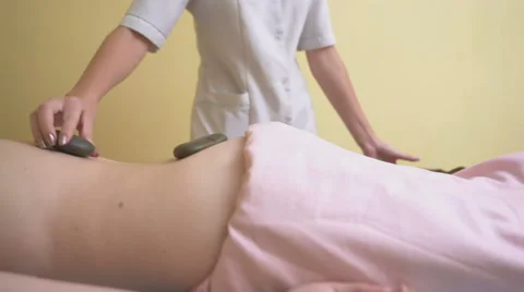 Massage Master puts on the back of a young woman hot stones Stock Footage 68968502