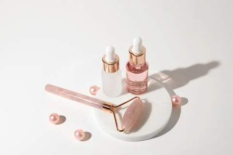 Massage quartz roller and two glass bottles of cosmetic liquid transparent gel Stock Photos