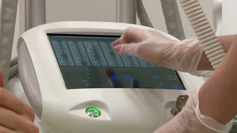 The massage therapist dials the program on the medical device Stock Footage 148167005