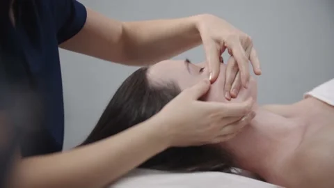 Massagist doing a face massage using her fingers on the clean skin of her female Stock Footage 168812091