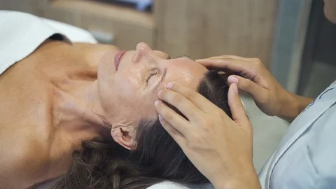 Massagist start to work by hands from temples and then continue lower to chin Stock Footage 111018498