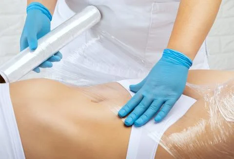The masseur does a full body wrap cosmetic procedure in a beauty salon. Spa t Stock Photos