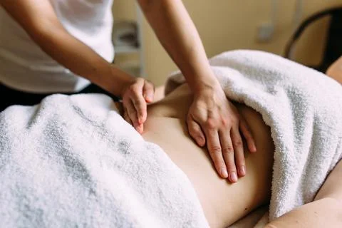 The masseur gives a massage to the female belly at the spa. Stock Photos