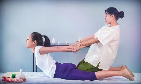 Masseur is giving back stretching pulling hand of a woman in Thai Massage Spa 库存照片