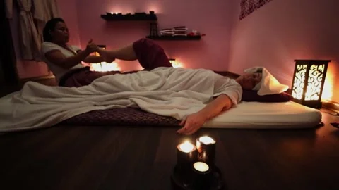 Masseur pulls leg of client which lies on mattress in spa center Stock Footage 276377826