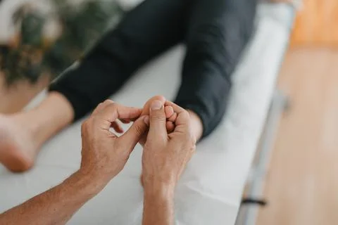 Masseur's hands doing reflexology on a woman's feet Stock Photos