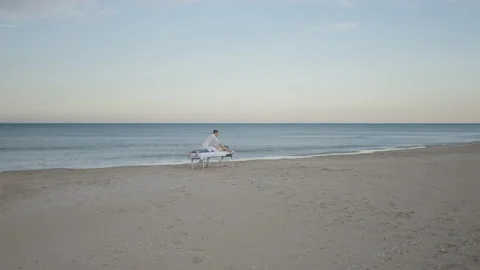 Masseuse and his client at the empty beach during dawn time. Healing and Stock Footage 217412066