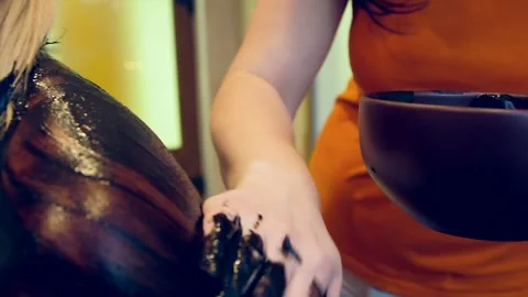 Masseuse Apply and Gently Massage Black Mud into Woman's Shoulders and Back Stock Footage 293746048