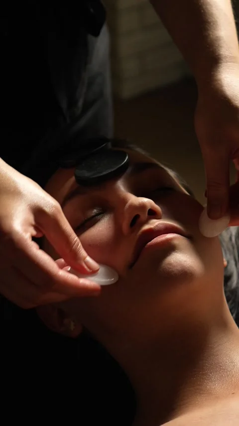 Masseuse does professional stone facial massage with stones. slides stones and p Stock Footage 328613383