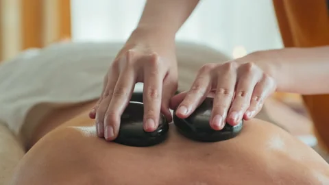 Masseuse Doing Hot Stone Massage to Woman in Spa Stock-Footage 233566329