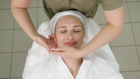 Masseuse hands move doing calming face massage upper view Stock Footage 119808264