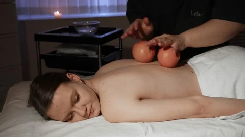 Masseuse makes a massage with an orange to a young woman Stock Footage 236983491