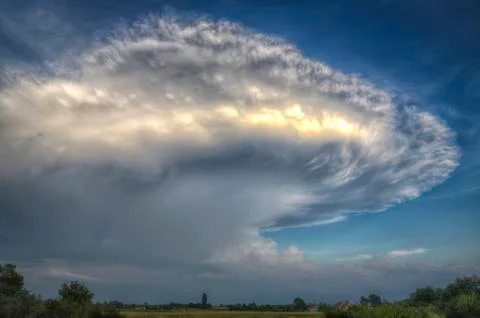 Massive anvil cloud or cumulonimbus incus oer a villlage landscape Stock Photos