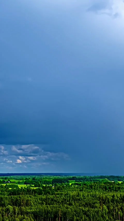 Massive Blue Storm Cloud and Distant Rainfall Above Forest and Farmland Stock Footage 344028408